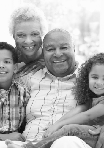 african american grandparents with grandchildren on couch smiling at camera