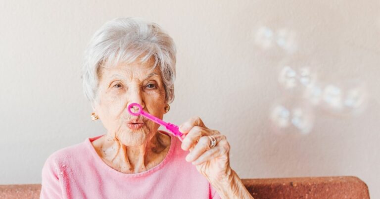 senior woman in pinks shirt blowing bubbles